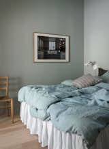 One of the two bedrooms in the home. Featuring a calming shade of green, the space breaks away from the all-white palette on the lower level. A full bathroom is located steps away.  Photo 8 of 12 in Hem Founder Petrus Palmér Says “Adjö” to His Converted Blacksmith’s Workshop in Stockholm