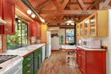 Here is a peek at the kitchen, featuring a mix of red and green cabinets over reclaimed hardwood floors. A repurposed stovepipe stands in for standard track lighting above the sink.  Photo 4 of 10 in A Funky ’70s House Owned by Nancy Wilson of Heart Lists for $1.2M Near Seattle