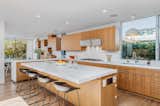 A closer look at the kitchen. Custom wooden cabinets wraps around the space, contrasted by white countertops and sleek, modern finishes.  Photo 4 of 14 in This House With Larger-Than-Life California Poppies on Its Facade Just Hit the Market for $3.4M