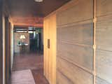 Floor-to-ceiling windows and built-in storage line opposite sides of a hallway leading to the two bedrooms. Wright replicated the wall design with chain-linked boards that fold down to reveal individual compartments.