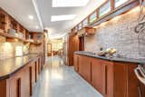 The modern, galley-style kitchen features original brick walls and clerestory windows on both sides. Numerous skylights also help to brighten the space.