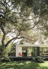 Sliding glass doors and a deck connect the minimalist dwelling to the lush backyard with a giant oak tree. The structure, known as Menlo Park Connect2, was built by Connect Homes.