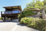 A view of the front facade shows the carport under the deck. The home's two-car garage is located further up the driveway, on the opposite side of the carport.  Photo 17 of 19 in An Alluring Berkeley Hills Home by a Case Study Architect Asks $2.9M