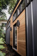 Exterior and Tiny Home Building Type Two bands of clerestory windows run along the front facade, where a single glass door is flanked by simple light fixtures to complement the metal cladding.  Photo 14 of 14 in A Hawaii-Based Couple Build a Luminous Tiny House in Just 25 Days