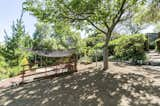 At canopy-covered patio is located in another corner, adjacent to raised vegetable beds.