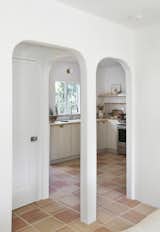 A pair of arched doorways lead to a bathroom on the left, and a kitchen with modern appliances on the right.