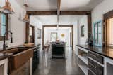 An updated kitchen fills one wing, offering stucco-and-wood cabinetry topped by mahogany butcher-block counters. Other features such as the copper sink and fixtures complement original post and beams.