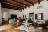 A large living area sits in the center of the home and looks out onto the courtyard. Features of the space include an original timber-beamed ceiling and hardwood floors.