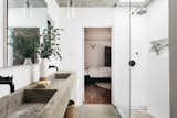 Concrete sinks and flooring complete the modern bath, which is also illuminated by a skylight above the shower.