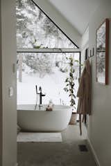 The master bathroom mirrors the window design. A soaking tub from Wetstyle provides a spot to unwind and enjoy the view.