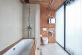 A wood surround encloses a large soaking tub and shower.  Photo 9 of 11 in A Penthouse Apartment in a London Water Tank Offers Utilitarian Style for $781K