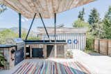 The covered patio offers an outdoor prep area with built-in grill and sink. A detached garage can be seen in the background.  Photo 10 of 22 in An Arty Couple Say Goodbye to Their Handcrafted, Net-Zero Shipping Container House for $3.15M