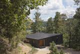 A black bent steel plate stair leads up three steps to a notched entry paneled in clear-stained cypress.