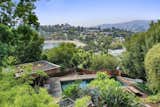 A view looking over vegetable beds shows the pool and guesthouse down below, as well as the Ivanhoe Reservoir and Hollywood Hills in the distance.  Photo 20 of 24 in Asking $3.75M, This Bohemian Hillside Home in L.A. Comes Complete With a Potter’s Studio