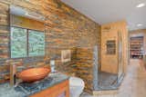 The en suite bathroom features soapstone counters, a vessel sink, and walls clad in stone tile.