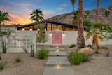 Complete with a decorative block wall and pink front door, the home's front facade looks picture-perfect against a backdrop of the desert landscape.  Photo 17 of 17 in A Palm Springs Alexander Home Sings After a Chic Renovation and Hits the Market to the Tune of $2.1M