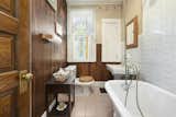 The charming full bathroom features a clawfoot tub, pedestal sink, and stained-glass window.