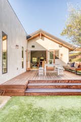 The deck features space for outdoor dining and built-in seating to one side. The original home transitions into a rectangular, modern addition that extends from the rear.