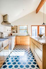 The kitchen features ample wood cabinetry, hexagonal tile flooring in a saturated blue, and a vintage-style range.