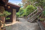 A small patio is also located along the front of the home, where a staircase leads up to a parking area near the street.