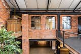 The upper level of the warehouse is intersected by a series of walkways and bridges that connect the residences and workspaces. A vintage elevator occupies a corner.