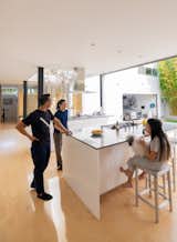 Sliding glass walls open the kitchen to the outdoor courtyard, providing more space for the Lai family to enjoy. The lower level has open sight lines to the courtyard and the garage, where a Genesis GV80 sits.
