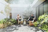 Accompanied by their dog, Gibson, in the gravel courtyard, Kristin and Jim relax on a Driade MT1 armchair and MT3 rocking chair, both by Ron Arad. “We value that modern ideal—where you can easily go outside and where small rooms feel bigger,” says Alter.