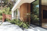 The wood cladding extends outside and wraps around a corner of the facade. Alemán Design Build oversaw the landscaping.