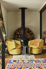 Two mustard Crescent swivel chairs and throw pillows from West Elm add a touch of color to the living area. Under the chairs, a steel plate from the original shipping container reminds everyone what the house used to be. The fireplace is Fire Drum 2 by Malm and the firewood holder is by David DeSantis.