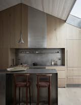 In the kitchen, Suzanne and her team opted for stainless steel along the countertops and backsplash. "It's a material that amplifies natural light while appearing more slender and lightweight compared to a thick stone slab," she says. An aluminum-lined lightwell also hangs over the space.