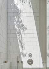 In one such instance, the shower wall acts as a canvas for a beam of sunlight entering from the skylight above. The bathroom’s crisp white tiles complement the home’s calm vibes.