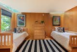 The bedroom features wood-clad walls and floors, along with two skylights and a large window.