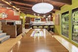 Another view of the dining area looks back toward the kitchen. New, full-height windows look out onto trees surrounding the home; a central staircase leads down to the basement.  Photo 6 of 11 in A Michigan Midcentury With Colorful ’60s Flair Lists for $319K