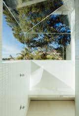 There is a spa-like quality to this shower, with its marble seating, white tile, and faceted glass enclosure.