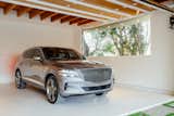 The garage is an integral part of the architecture with its exposed wooden beams and large picture window. Natural light fills the interior, where a Genesis GV80 is parked. 

Preproduction model with optional features shown.
