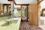 The en suite bathroom features a tiled vanity and sink as well as original cabinetry, and provides direct access to the private terrace.