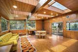 The solarium was added in the 1970s and features several large skylights and wraparound windows. Brown tiles cover the floor and extend up the wall around a corner fireplace.  Photo 7 of 15 in Moritz Kundig’s Historic Wallmark House Offers Lakefront Living for $1.1M