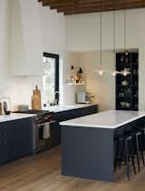 Kitchen, Marble, Range, Medium Hardwood, Range Hood, Open, Drop In, Pendant, and Wood In the kitchen, bar stools by Atelier Arking line a marble-topped island.  Kitchen Pendant Range Hood Open Drop In Photos from A Toronto Couple Turn an Abandoned Schoolhouse Into an Elegant Country Getaway