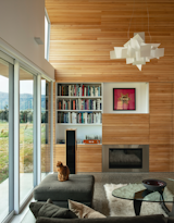 Living Room, Sofa, Ottomans, Pendant Lighting, Coffee Tables, Bookcase, Terrazzo Floor, Storage, and Gas Burning Fireplace  Photo 7 of 17 in A Musician Couple’s Wedge-Shaped House Echoes the Majesty of the New Zealand Landscape