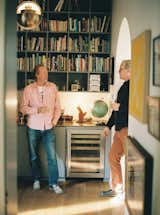 Chris, at left, and Techentin stand in the library, which they outfitted with a solid brass counter. The multi pendant is by Louis Weisdorf and the refrigerator is by U-Line.