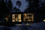 At night, the expansive windows and doors allow a warm light to emanate into the remote forest.
