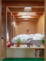 A closer look at the partly enclosed sleeping area, which is illuminated by a small skylight. Custom cabinetry offer deep storage units as a way to help maximize the studio's layout.