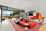 A look at one of the home's several living areas, which features a connected outdoor patio. Bright colored furnishings pop against the surrounding crisp white walls.