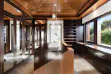The primary suite also includes dual dressing rooms, both of which are decked out with custom cabinetry and feature wooden vaulted ceilings, along with a central storage island.