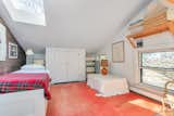 A peek at one of the four bedrooms, where the crisp, white ceiling complements an original wood-paneled wall. A large, wide window overlooks sculptures displayed in the backyard.