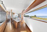 A central peninsula extends from built-in cabinetry in the dining area to the kitchen. A linear window frames the view along one side.