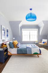 A boy’s bedroom by Chango &amp; Co. pairs a queen bed from Crate and Barrel with a bulbous blue light from Hive. The wallpaper is from Holly Hunt.