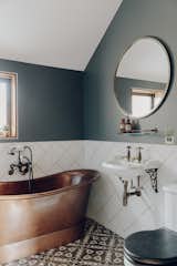 The hall bathroom offers a copper tub, patterned tile floor, and traditionally styled fixtures.