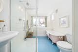 In the remodeled bathroom, the original pink clawfoot tub complements the vibrant blue floor.