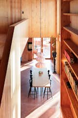 The two-story library wall that rises next to the dining area is one of the defining features of the interior. The shelves are made from glulam beams and contain storage along the base that the couple’s three-year-old daughter, Velaug, uses for toys.